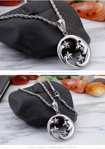 Macro detail of silver star and moon pendant with twisted chain on stone background