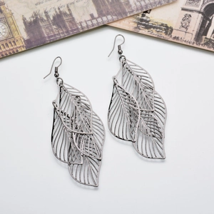 Minimalist gunmetal layered hollow leaf dangle earrings on a vintage prop background