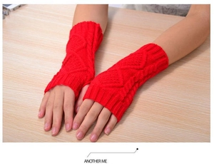 Close-up of red cable knit fingerless gloves with diamond pattern on wooden surface