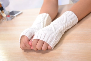 Detailed knit texture of white cable and diamond pattern fingerless arm warmers