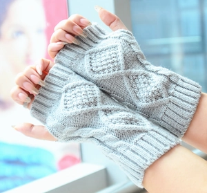 Close-up of light grey knit fingerless gloves with diamond and cable stitch texture