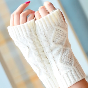 Gros plan de mitaines en tricot blanc à motif de torsades portées sur les mains