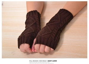 Close-up of coffee brown cable knit fingerless gloves with texture on wood background