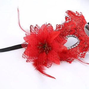 Close-up of a red lace Halloween mask featuring decorative feathers and sparkling rhinestones