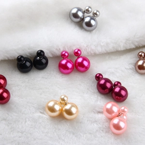 Gros plan de boucles d'oreilles perles double face colorées sur fond de fausse fourrure