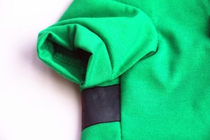 Close-up of vibrant green knitted dog shirt featuring black trim and precise stitching