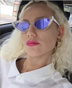 Cat eye sunglasses with purple mirrored lenses and gold screw detail earrings on model
