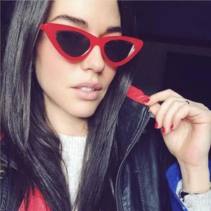 Close-up of vintage red cat-eye sunglasses with dark lenses worn by a model