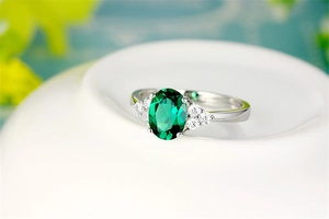 Close-up of vintage oval emerald gemstone ring with side diamond accents on silver band