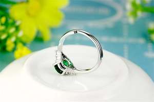 Close-up of adjustable silver ring with emerald-cut green stone and side diamonds