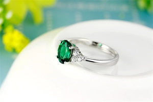 Macro detail of S925 silver ring with oval green emerald and side white zircon stones