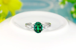 Macro view of vintage oval emerald ring with side diamonds on silver metal band