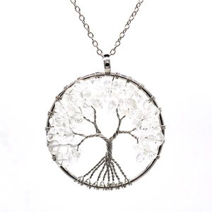 Macro view of a silver Tree of Life pendant with white crystal chips on white background