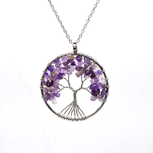 Detailed view of silver tree of life pendant with amethyst stones on a white background