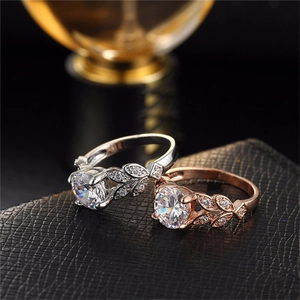 Detailed view of silver and rose gold leaf-shaped rings with sparkling zircon on leather