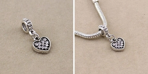 Detailed view of silver heart charm with crystals on a snake chain bracelet