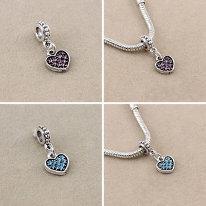 Detail of silver heart charms with purple and blue rhinestones on a snake chain bracelet