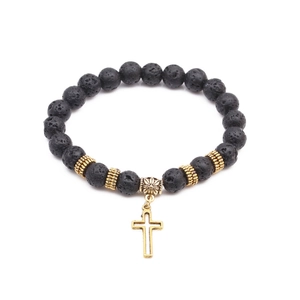 Detailed close-up of porous black lava stone beads with a golden metal cross pendant