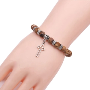 Detail of yoga bead bracelet with brown stones and silver cross charm on wrist