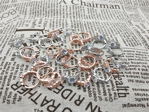 Detailed view of silver and rose gold leaf rings with round cubic zirconia on newspaper