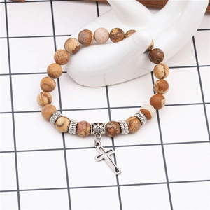 Detailed view of a brown beaded yoga bracelet with a silver cross pendant on a hand model