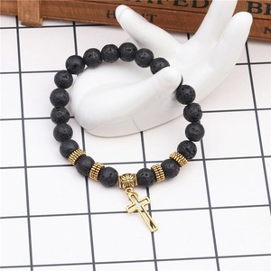 Detailed macro view of black volcanic stone beads with a golden cross charm on a bracelet