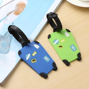 Blue and green silicone luggage tags with 3D embossed travel icons on wooden surface