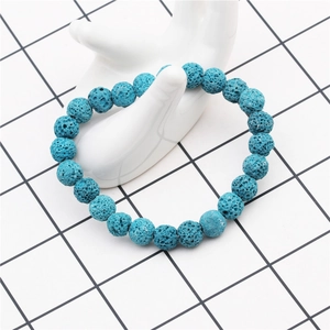 Detail of 8mm blue volcanic lava stone beads on a white ceramic hand display model