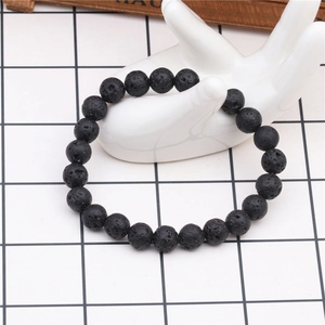Detail of 8mm black volcanic lava stone beaded bracelet on white ceramic hand model