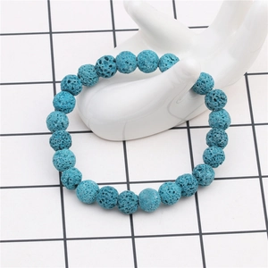 Close-up of 8mm blue porous lava rock beaded bracelet worn on a white ceramic hand model