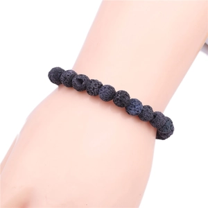 Detail of 8mm black volcanic lava stone beaded bracelet worn on a female wrist