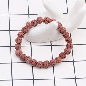 Detailed view of 8mm red volcanic lava stone beaded bracelet on ceramic hand display