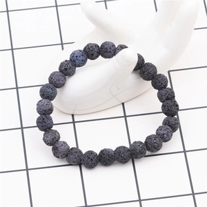Close-up of 8mm dark grey volcanic lava stone beaded bracelet on white hand model
