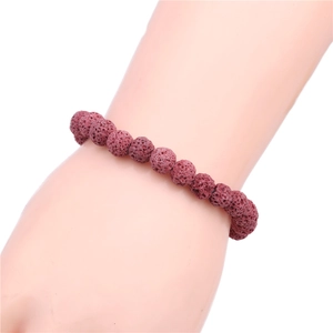 Macro detail of red lava stone beaded bracelet showing natural porous texture on wrist