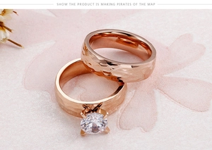 Close-up of hammered rose gold rings with a sparkling round gemstone on pink background