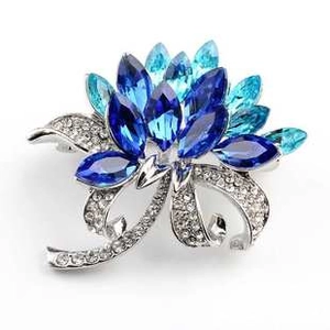Exquisite close-up of a blue crystal flower brooch with silver-toned rhinestone leaves