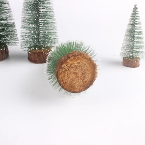 Macro shot of miniature snowy Christmas tree with white-tipped needles and wooden base