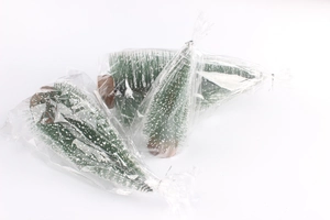 Close-up of mini snow-tipped bottle brush Christmas trees with natural wood bases