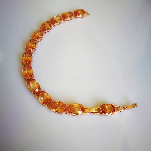 Detail of rose gold bracelet featuring vibrant orange oval-cut cubic zirconia gemstones