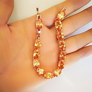 Detailed close-up of golden Venus bracelet with oval faceted orange-yellow zircon stones