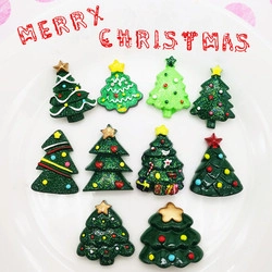 Macro view of green resin Christmas tree charms with glitter and star details on a plate