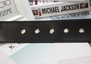 Detail of elegant black velvet belt with five gold metal eyelets and premium texture