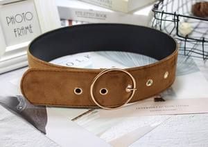 Close-up of brown velvet waist belt featuring a large gold circular metal buckle and eyelets