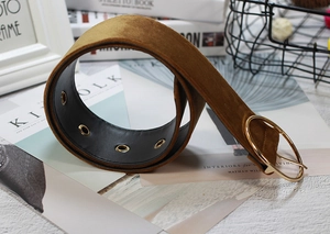 Close-up of brown velvet waist belt featuring a gold round buckle on vintage magazines