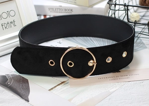 Detailed macro view of high-quality black velvet belt featuring a round golden metal buckle