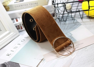 Close-up of brown velvet wide belt with round golden buckle on a vintage book background
