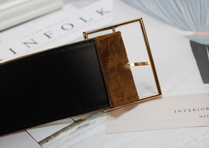 Detail of a wide black leather belt with brown velvet patch and square gold buckle