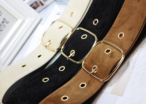 Close-up of three velvet waist belts in beige, black and brown with golden square buckles