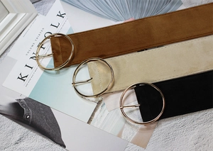 Close-up of velvet belts in brown, beige, and black with golden round buckles