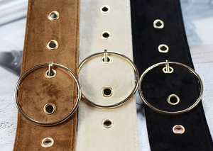 Close-up of velvet waist belts in brown beige and black with round gold metal buckles